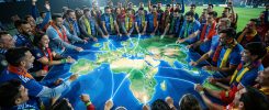 Des supporters et supportrices de football entourent une grande carte lumineuse reliant l’Europe, l’Afrique et l’Amérique du Sud.